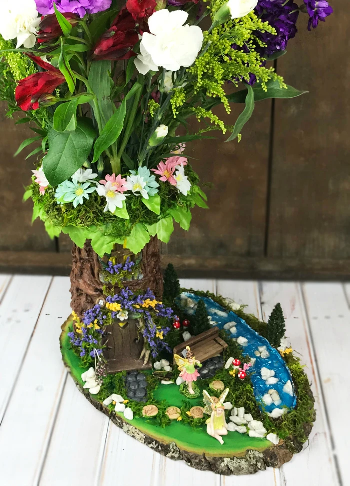 GORGEOUS! Learn how to transform a florist's vase into a beautiful fairy garden tree vase! This DIY fairy garden vase is absolutely stunning. Get all of the project details in this post!